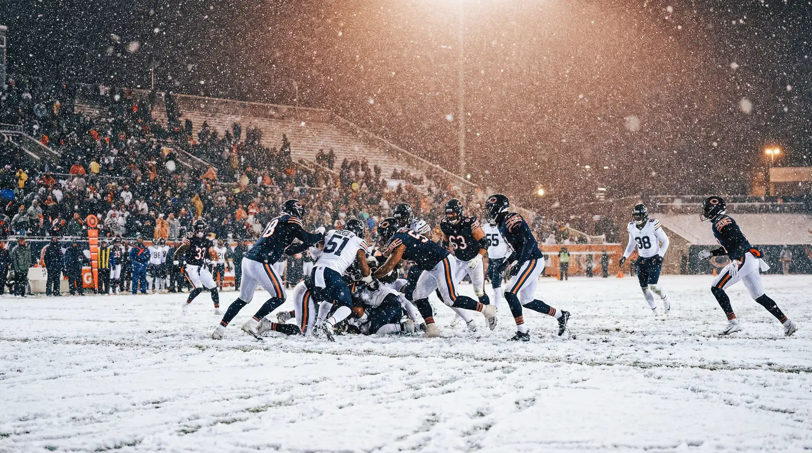 Partido de fútbol americano bajo una fuerte nevada con jugadores en el campo cubierto de nieve